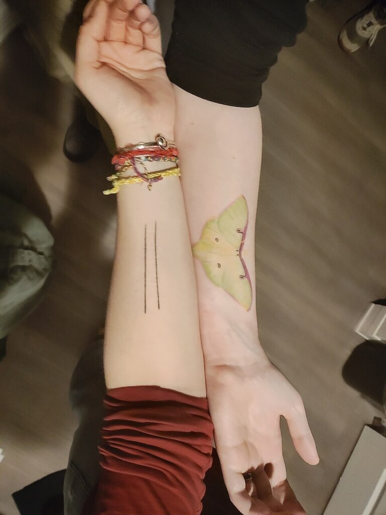 Luna moth tattoo placed over scars on the forearm