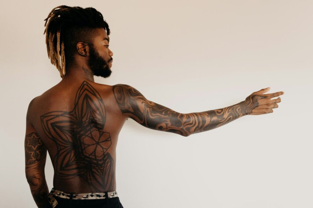 Man with tattoos on his back and outer arm, low pain areas