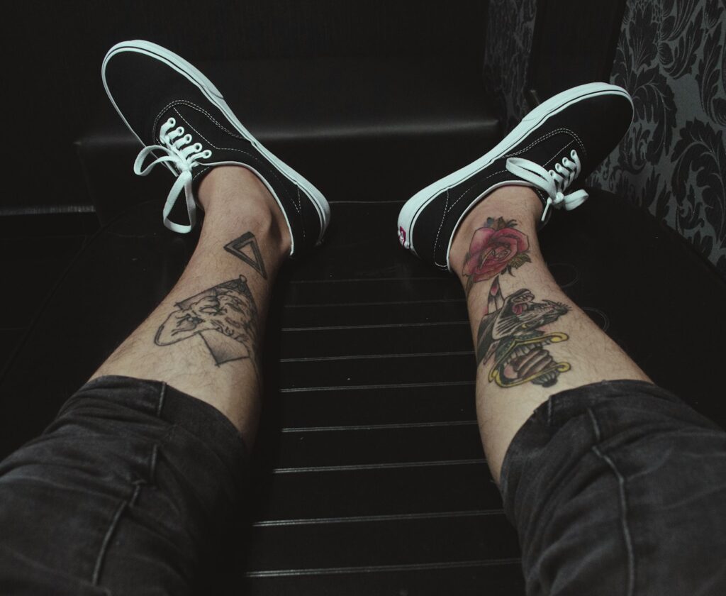 Line art tattoos on both ankles above sneakers