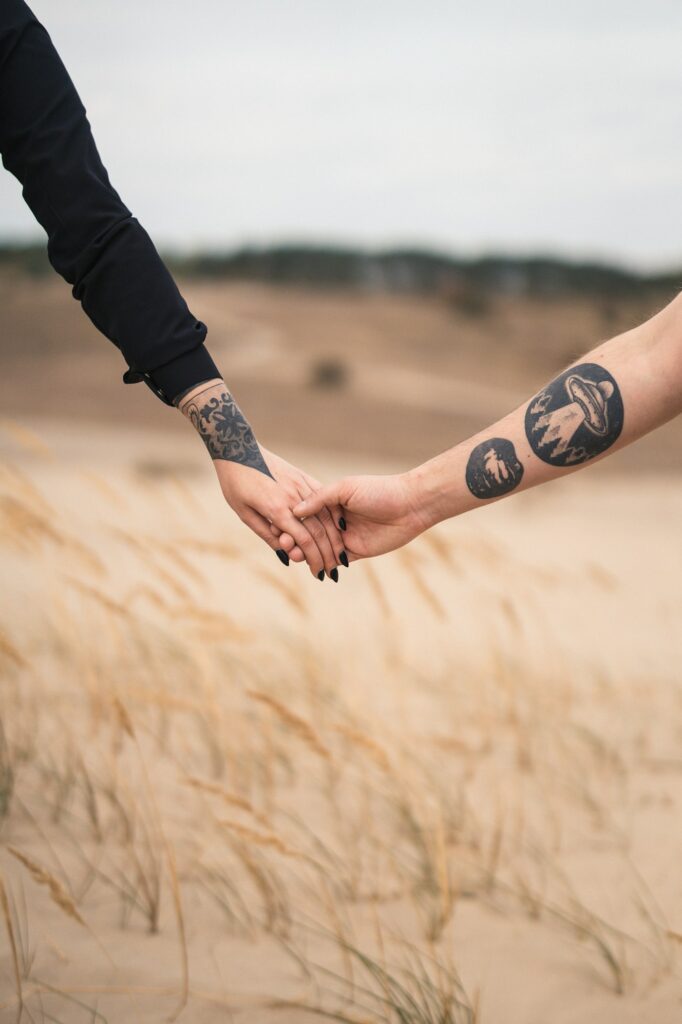 Two people holding hands with matching circle tattoos