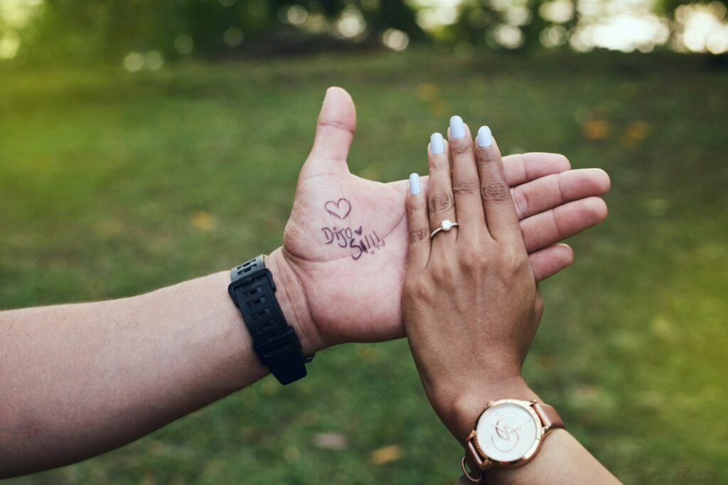 Two hands with small matching script and heart tattoos