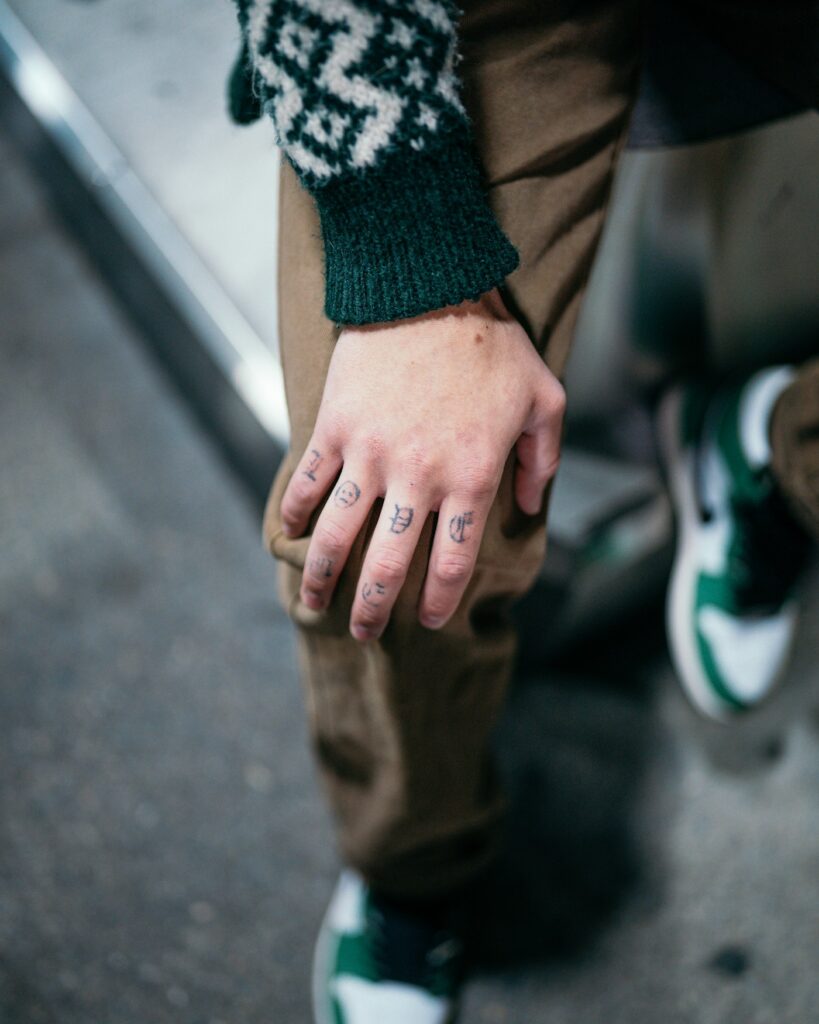Small minimalist tattoos on the fingers of a man's hand
