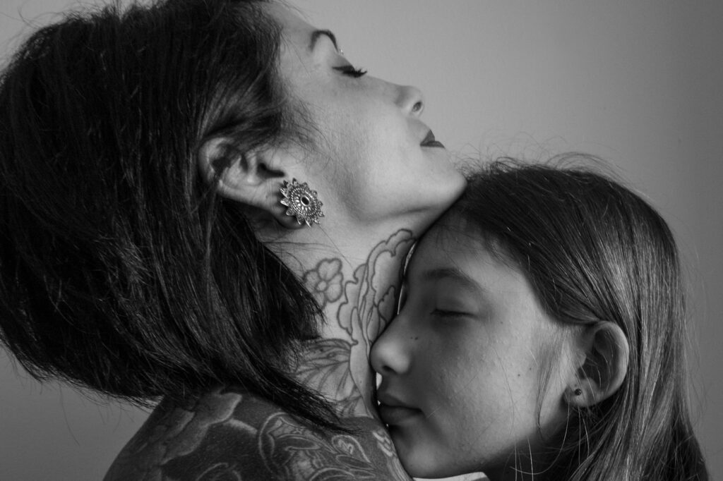 Tattooed mother hugging her daughter