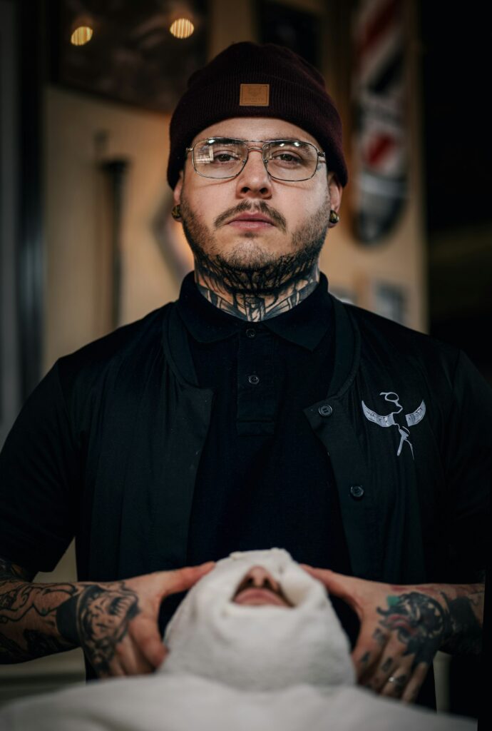 Bold neck piece tattoo on a man wearing glasses