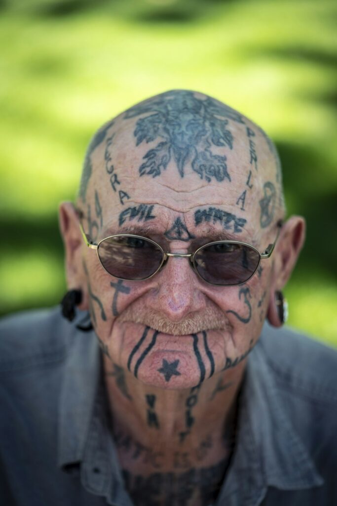 Older man with decades old face and head tattoos