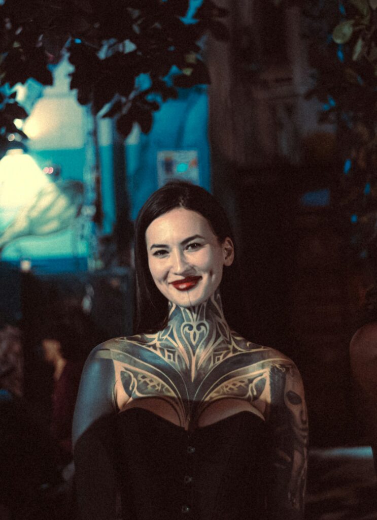 Ornamental throat and chest tattoo on a woman in a corset