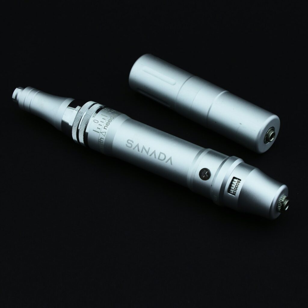 Two pen style tattoo machines on a dark background