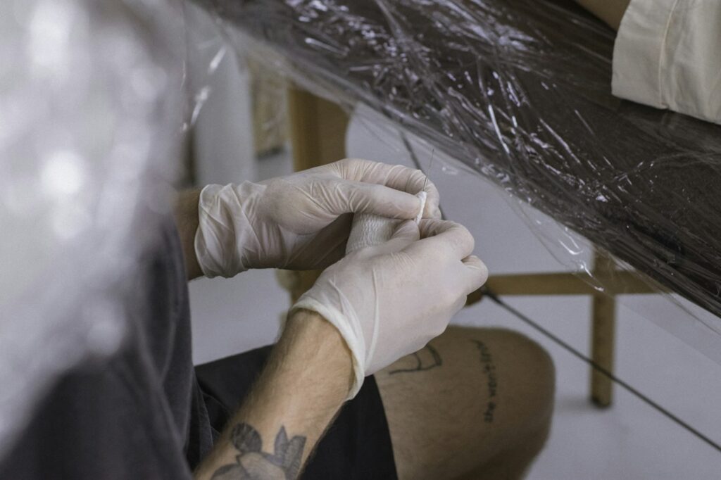Gloved hands wrapping a fresh tattoo in plastic