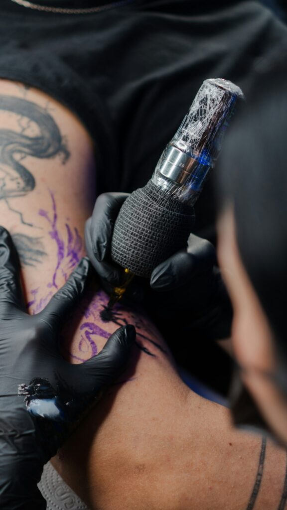 Tattoo with purple and blue watercolor wash being inked