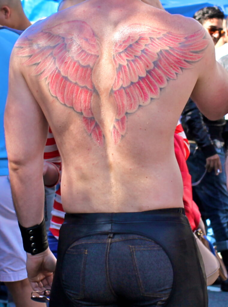 Red angel wings tattoo across a man's shoulder blades