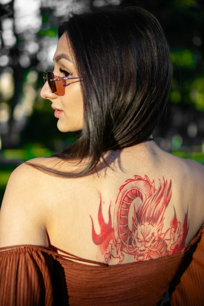 Red dragon tattoo across a woman's shoulder blades