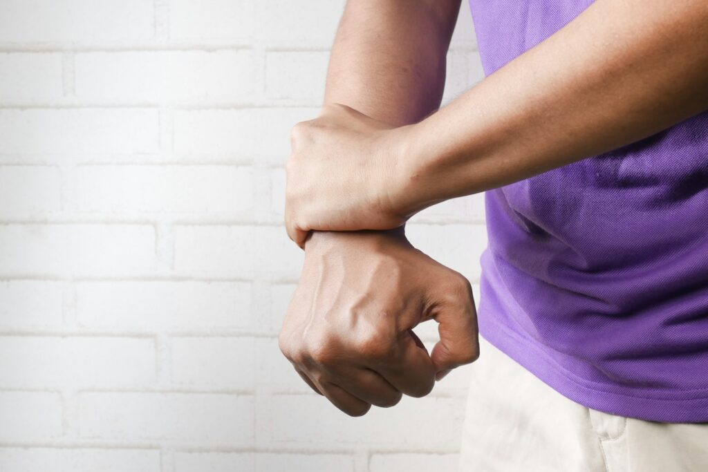 Person holding their wrist to resist scratching an itch