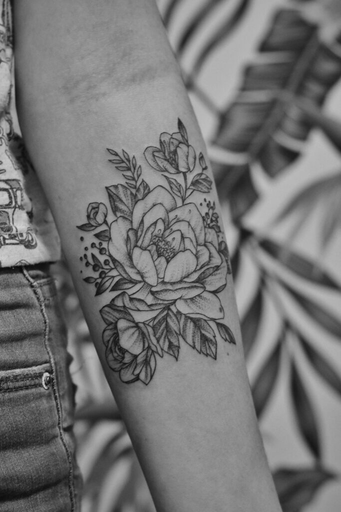 Rose tattoo meaning: black and grey rose tattoo on the arm