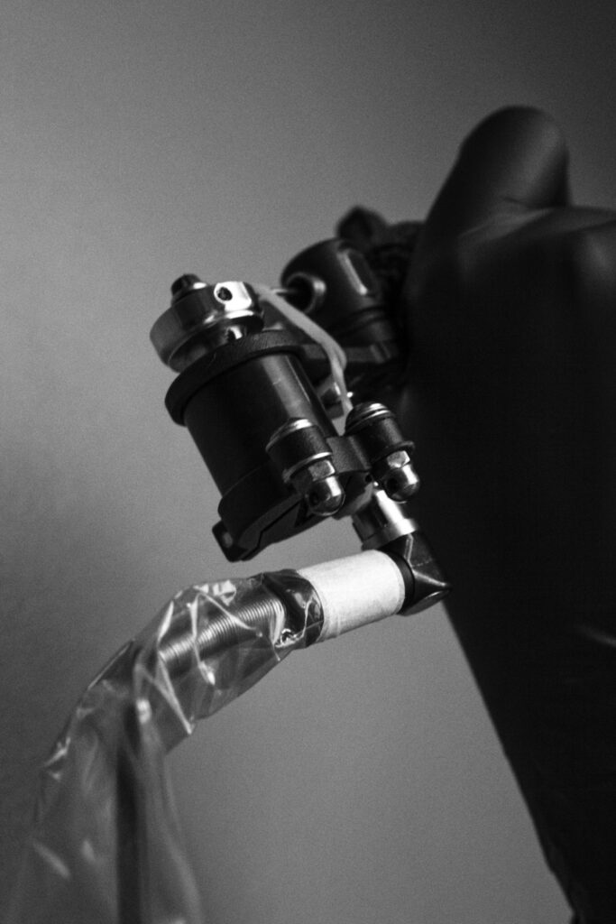 Black rotary tattoo machine in a gloved hand