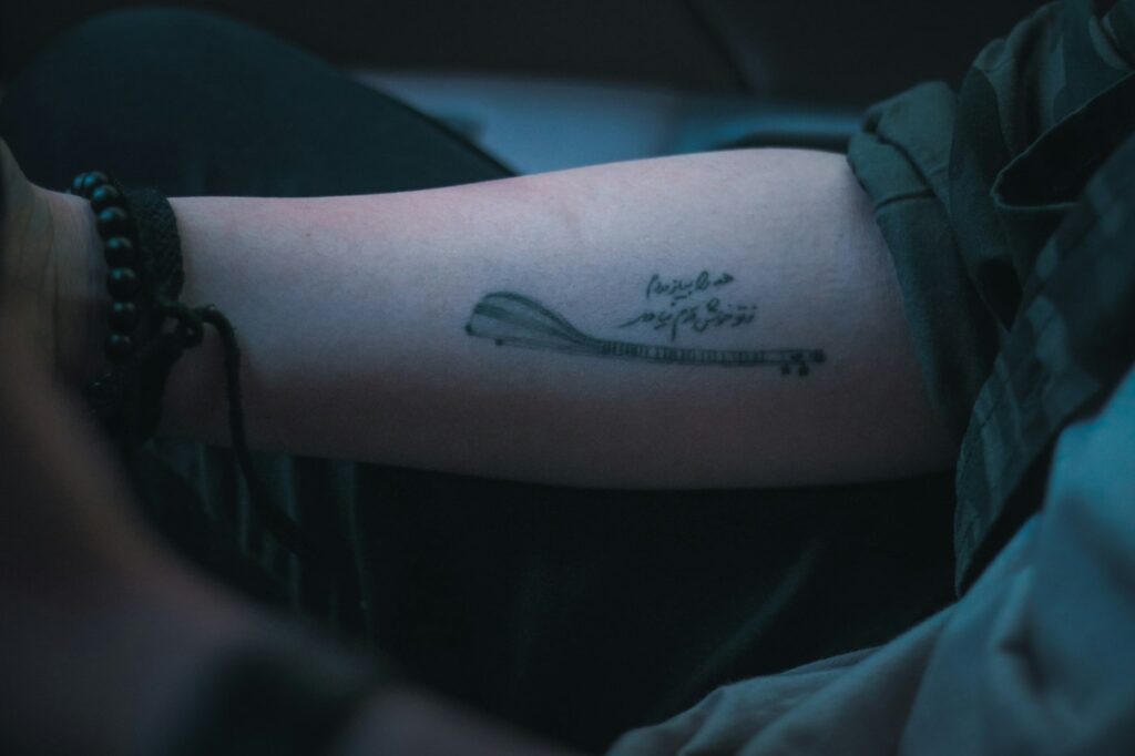 Fine line script with a small drawing on the forearm