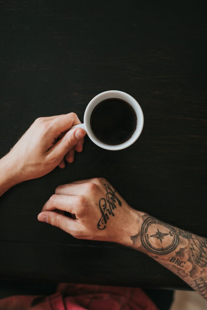Script tattoo on the back of the hand with a compass on the wrist
