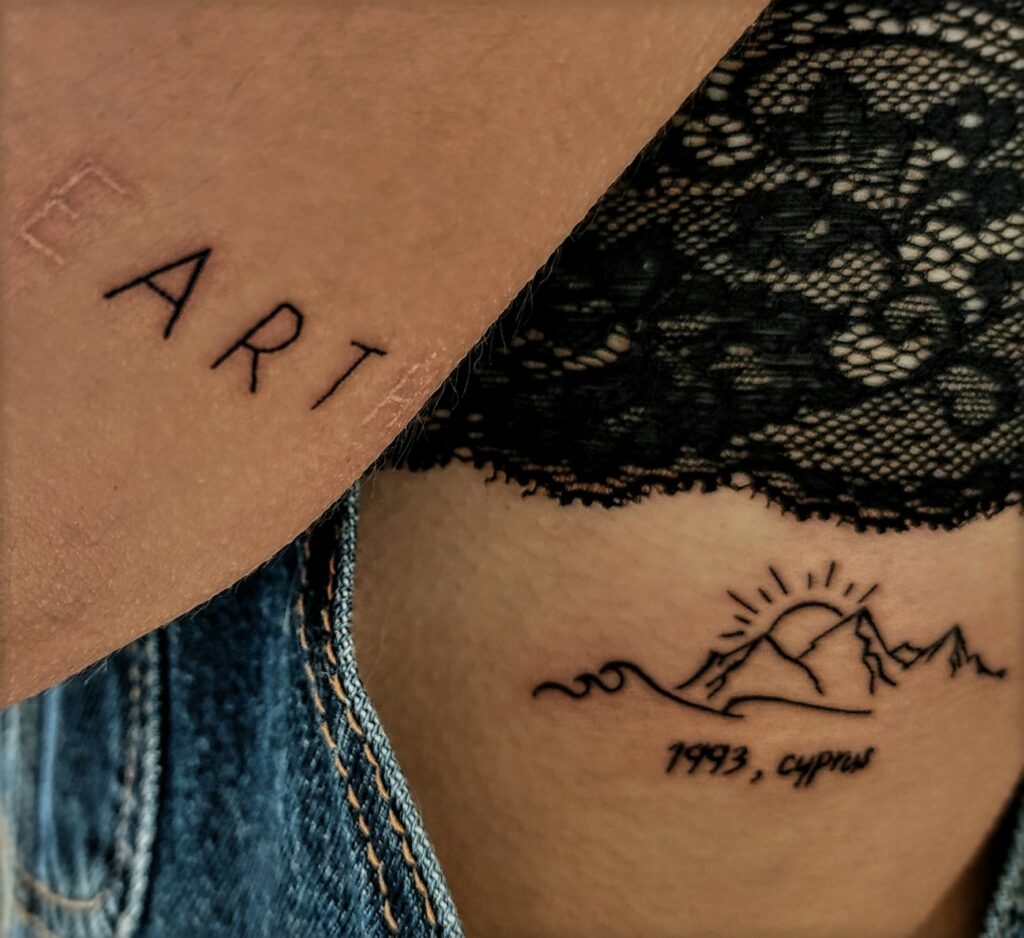 Script and mountain line tattoo on a woman's thigh