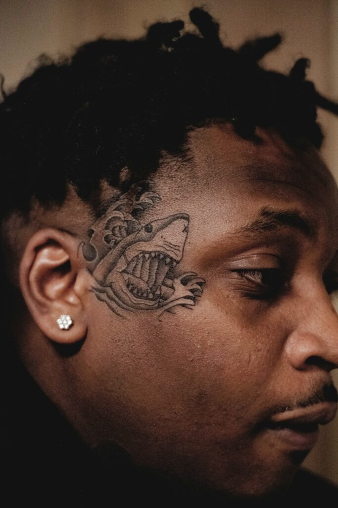 Shark head tattoo on the side of a man's face