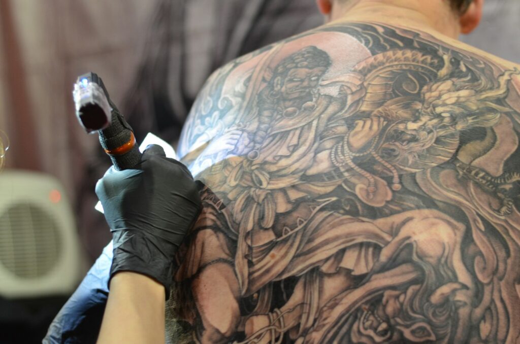 Large shoulder and back tattoo being inked