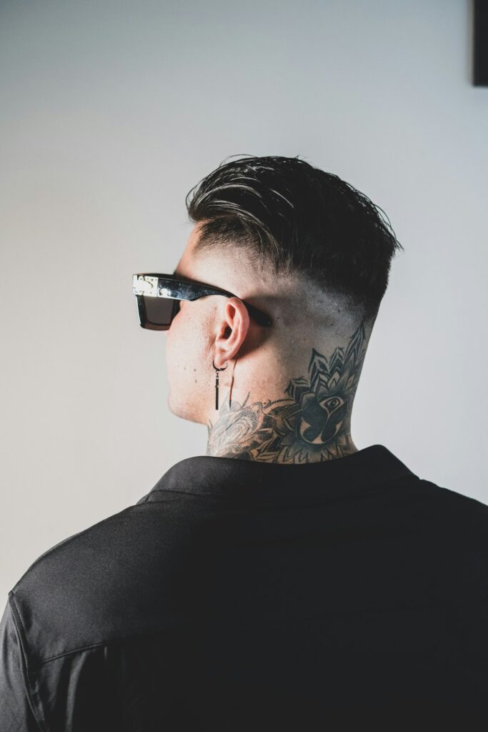Side neck tattoo on a man with a fade haircut