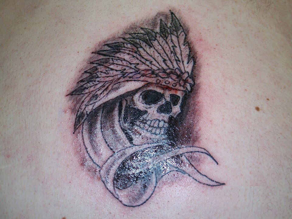 Skull wearing a feathered headdress tattoo