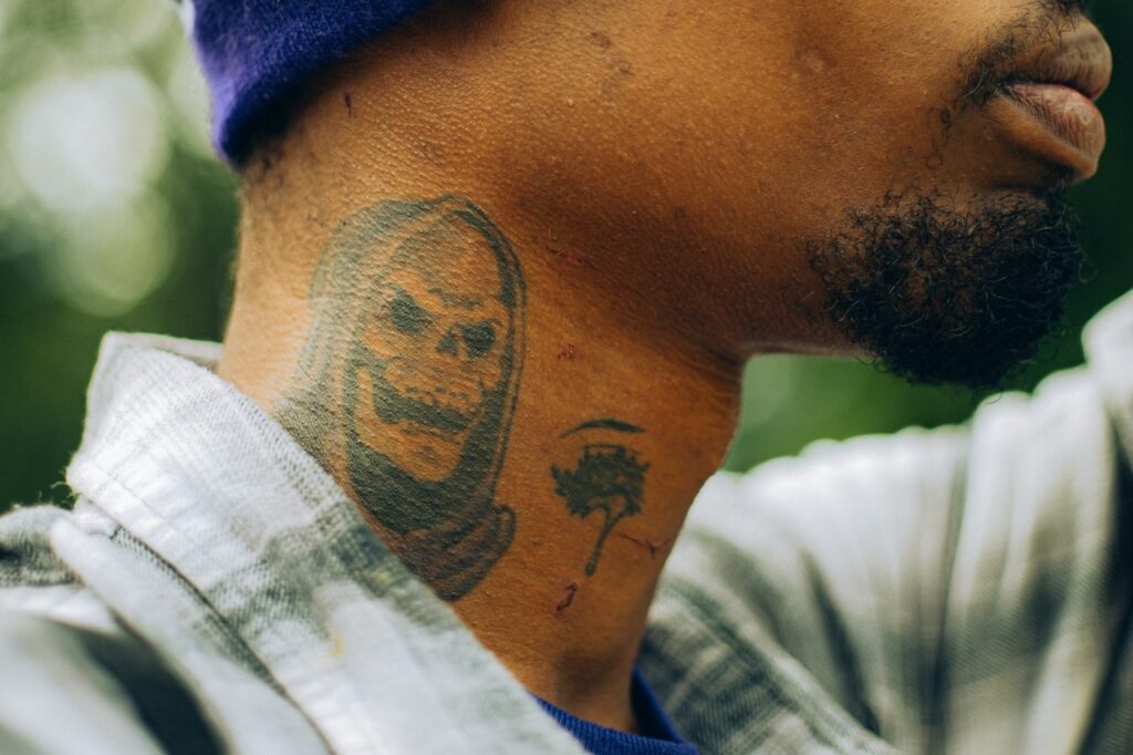 Black and grey skull tattoo on the side of a man's neck