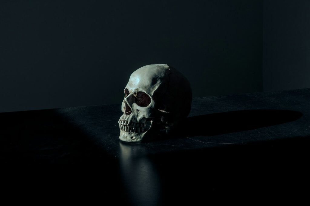 Skull tattoos for men: human skull in dramatic dark lighting