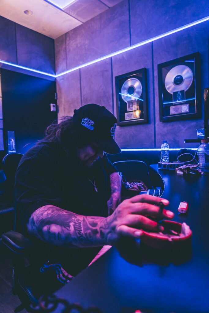 Sleeve tattoos for men: man with tattooed arms in a music studio
