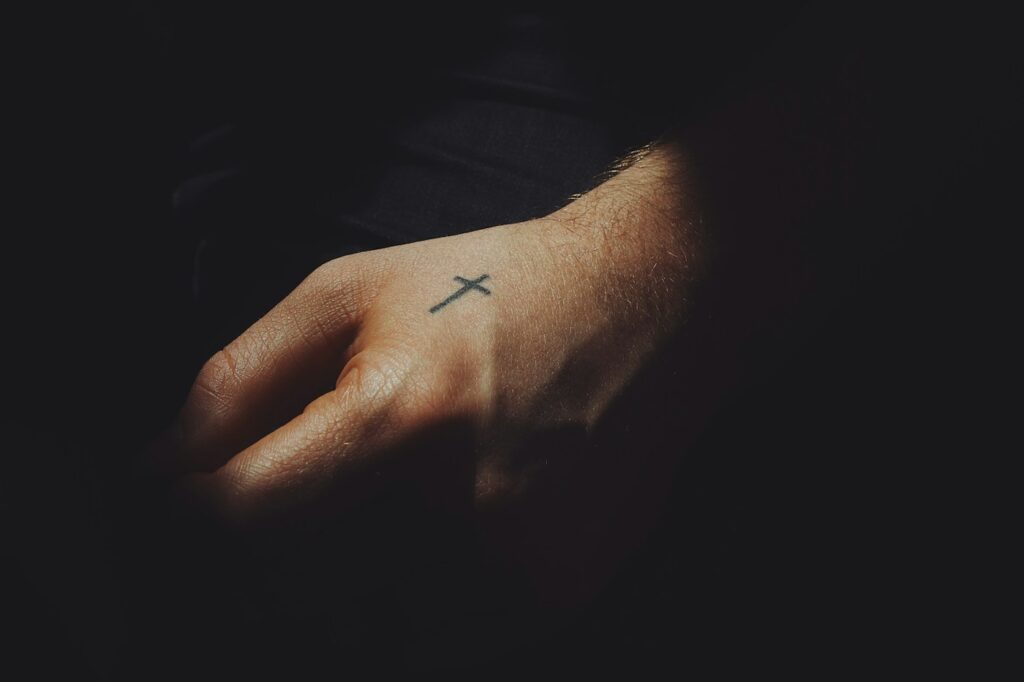 Christian tattoos for men: small cross on the side of the hand