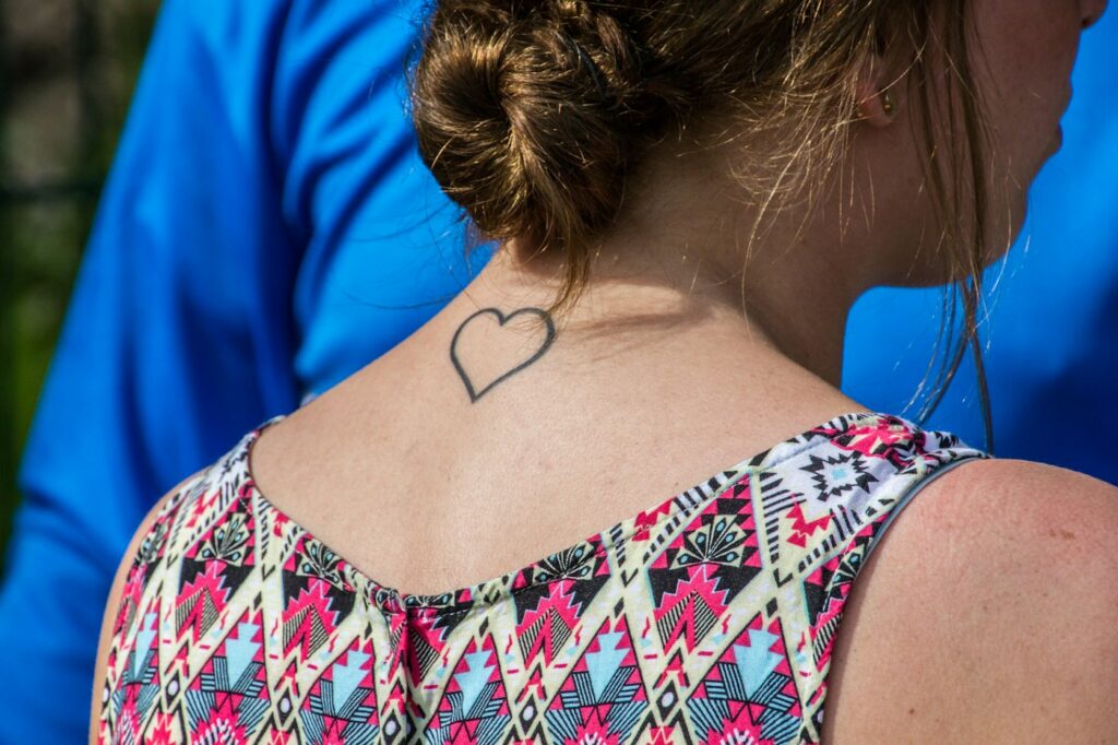 Small heart outline tattoo on the back of the neck