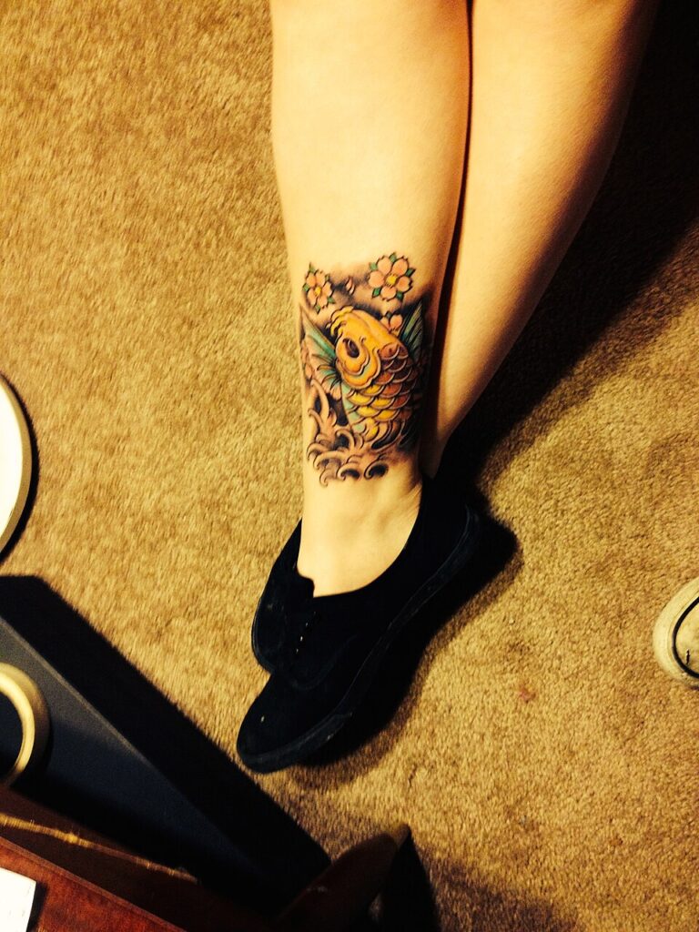 Koi fish tattoo: small black and grey koi on the lower leg