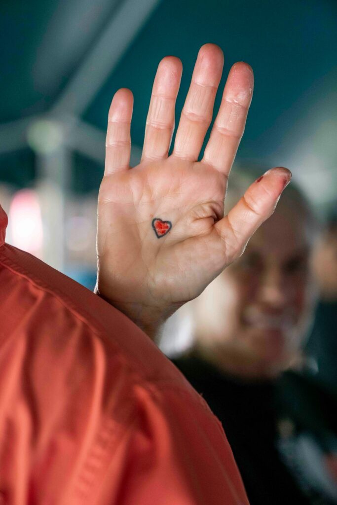 Small red heart tattoo on the palm of a hand