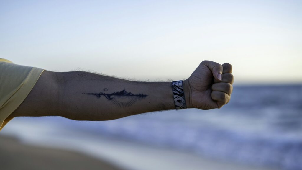 Shark tattoo: small black shark on a man's forearm