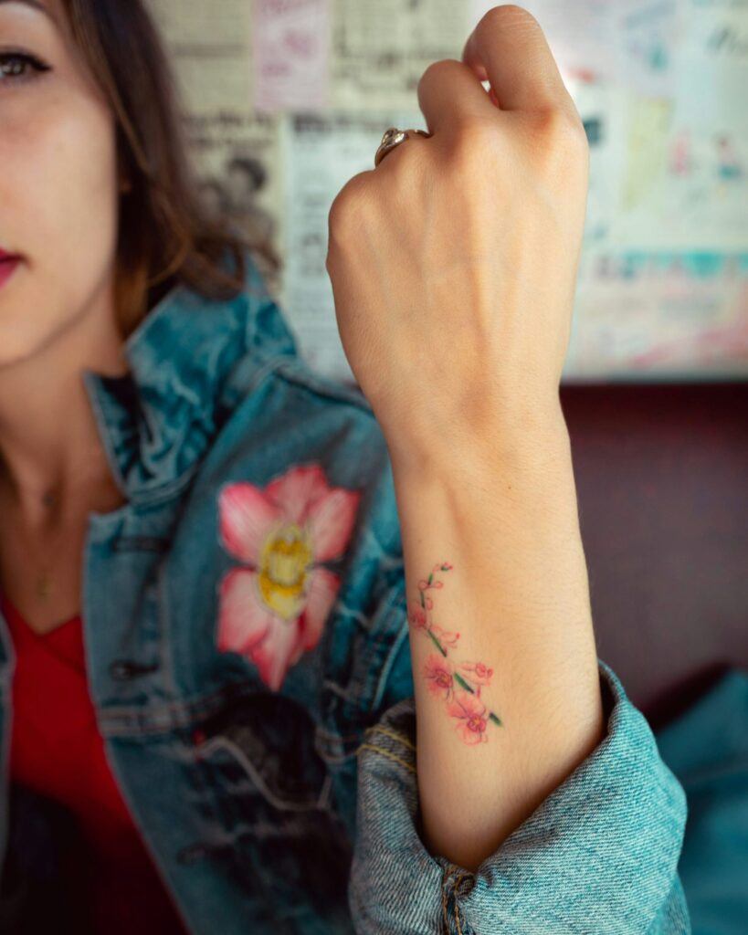 Watercolor tattoo: small flower on a woman's forearm