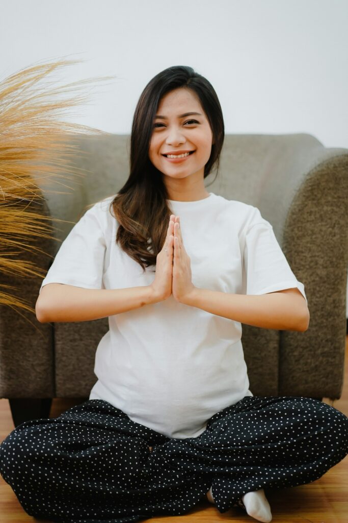 Smiling pregnant woman sitting calmly with hands together