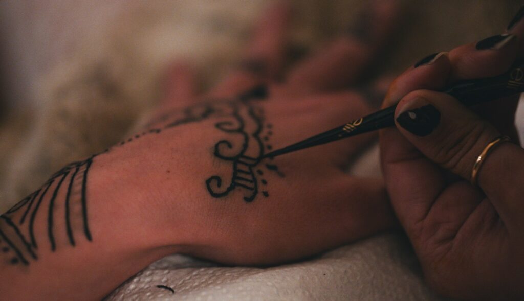 Stick and poke tattoo: professional hand poke artist tattooing a design on the hand