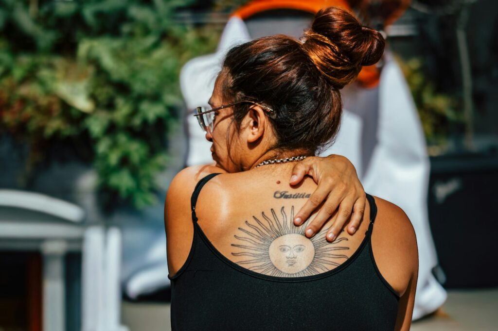 Sun face tattoo on a woman's upper back