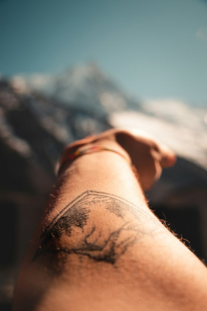 Black and grey wrist tattoo on a man in the mountains