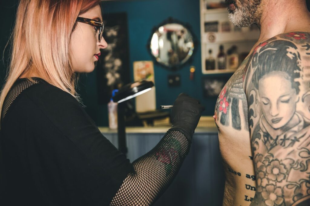 Tattoo apprenticeship: tattoo artist working in a studio on a client's arm
