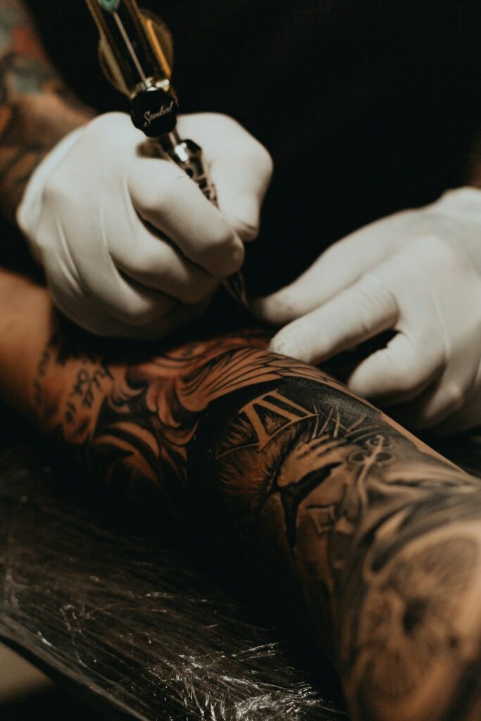 Tattoo artist tattooing a client's arm
