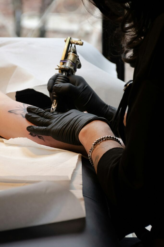 Tattoo artist in black gloves starting the outline of a tattoo