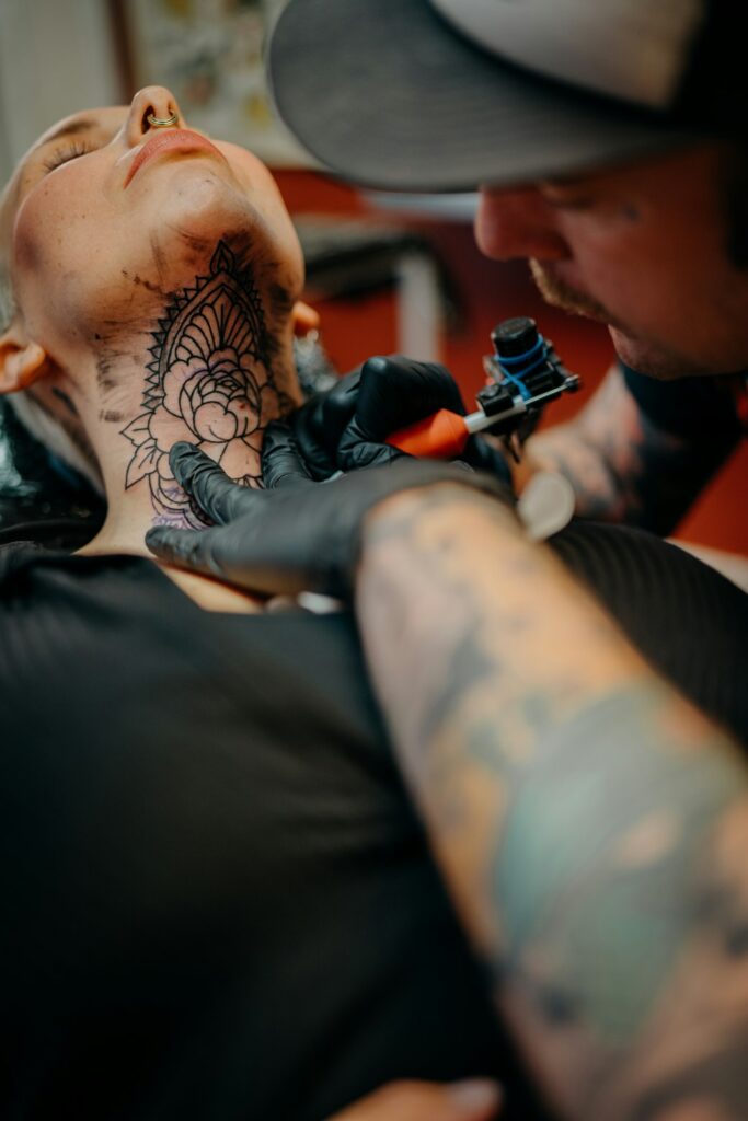 Tattoo artist working on a client's neck, one of the more painful spots