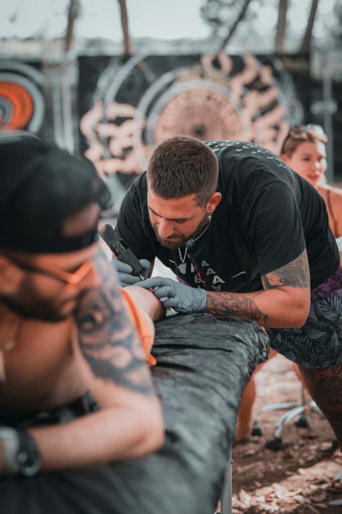 Tattoo artist working on a client lying on a padded bench