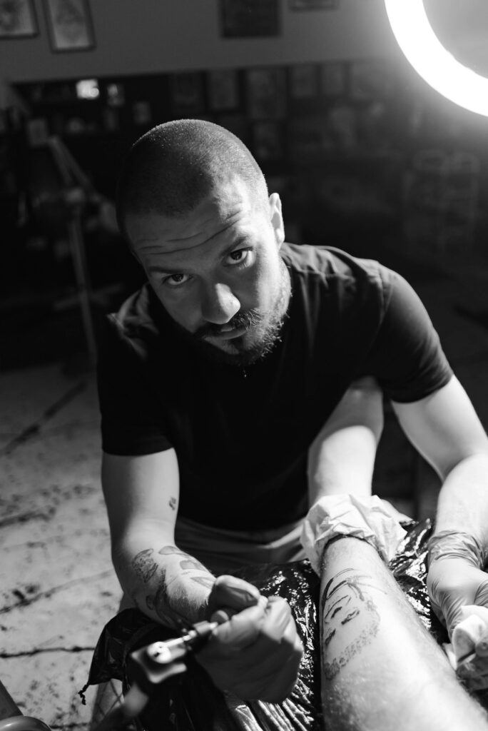 Experienced tattoo artist working carefully on a client's leg