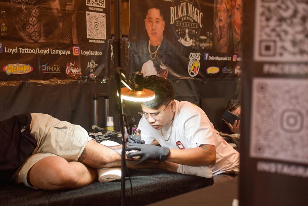 Tattoo artist working on a client lying on a padded bench
