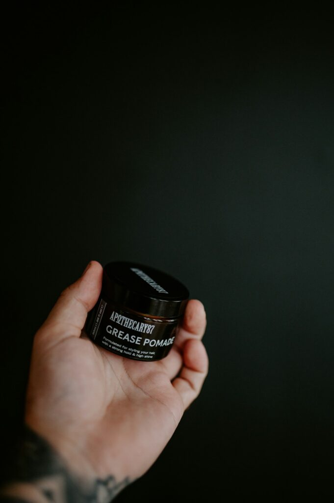 Jar of fragrance free tattoo balm held in a tattooed hand