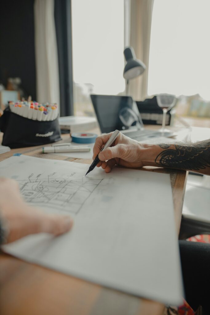 Tattoo artist drawing a design by hand at a studio desk