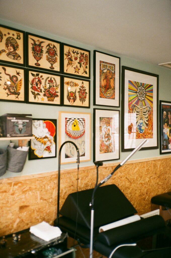 Framed tattoo flash hanging above a tattoo chair in a studio