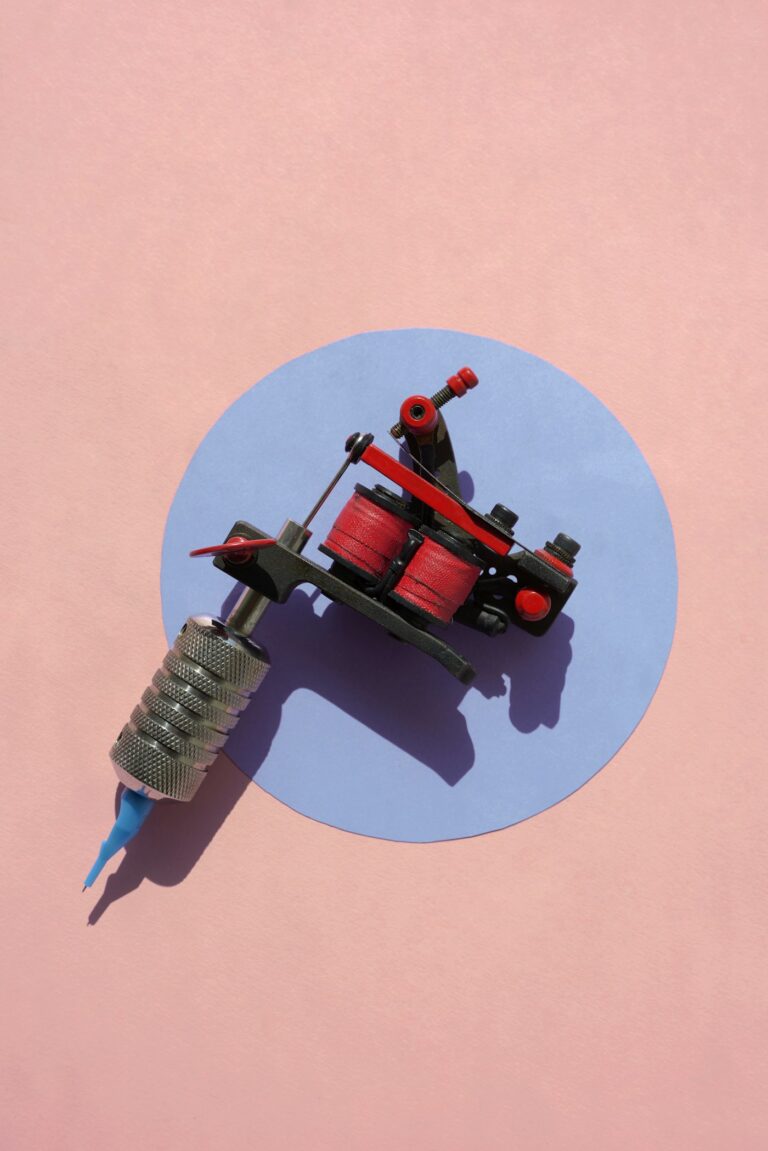 Tattoo gun: red coil tattoo machine on a pink and blue background
