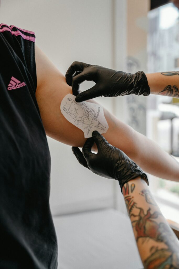 Tattoo healing process: artist applying a protective film over a fresh arm tattoo